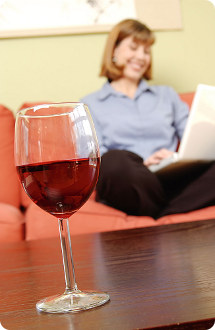 Frau mit Laptop und Weinglas